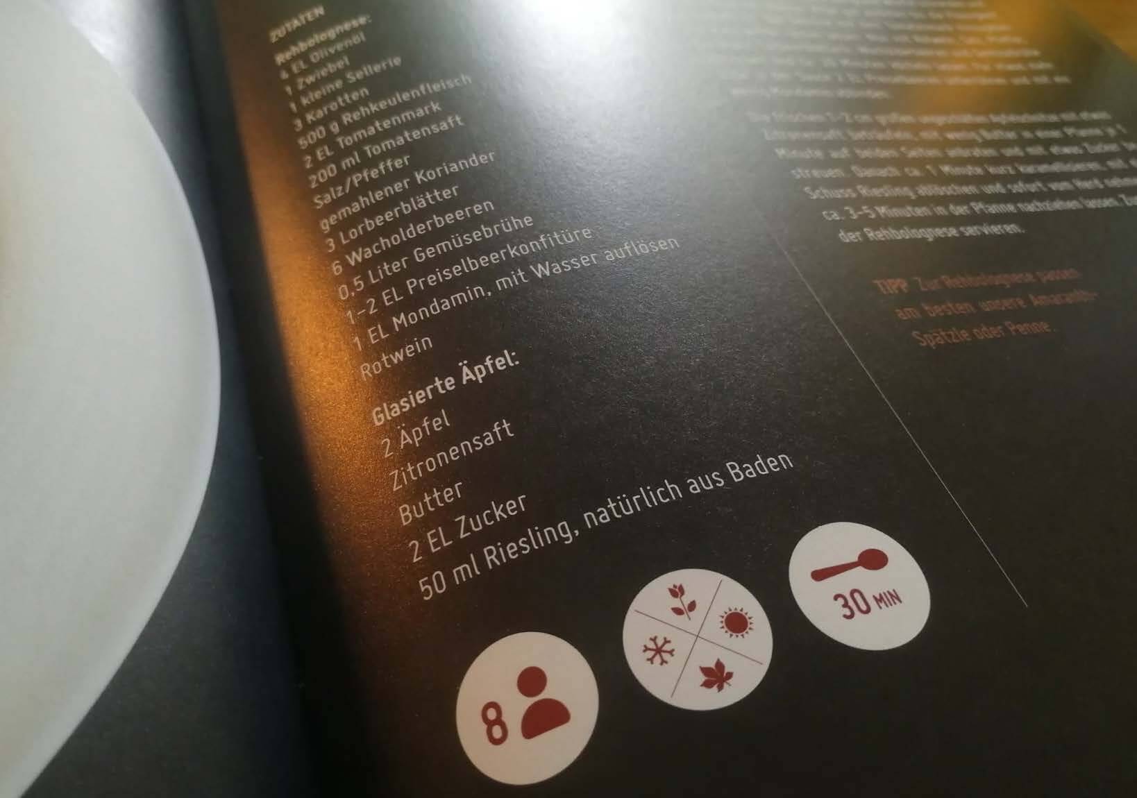 Rezeptseite für Rehbolognese aus dem Kochbuch: Zutatenliste mit Rehbolognese, Zwiebel, Karotten, Tomatenmark, Tomatensaft, Lorbeerblätter, Wacholderbeeren, Gemüsebrühe, Preiselbeerkonfitüre, Rotwein, glasierten Äpfeln, Zitronensaft, Butter, Zucker, Riesling, sowie Symbole für 8 Portionen, 30 Minuten Zubereitungszeit und Icons für Allergene