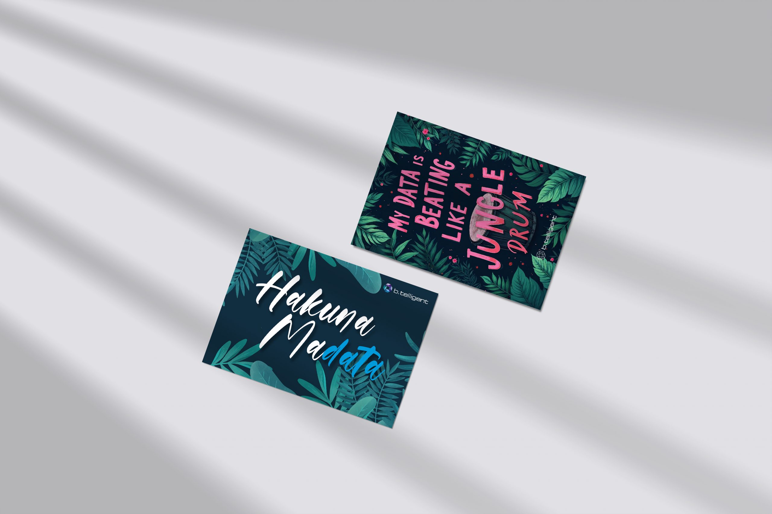 Postkarten-Set für b.telligent auf der FabCon Europe: Zwei Postkarten mit Dschungel-Motiv und Sprüchen ‚Hakuna Madata‘ sowie ‚My Data is Beating Like a Jungle Drum‘, umgeben von grünen Blättern und einer Trommel-Illustration. Entworfen von Rebekka Markert, Grafikdesigner:in für kreative Messe-Give-aways.