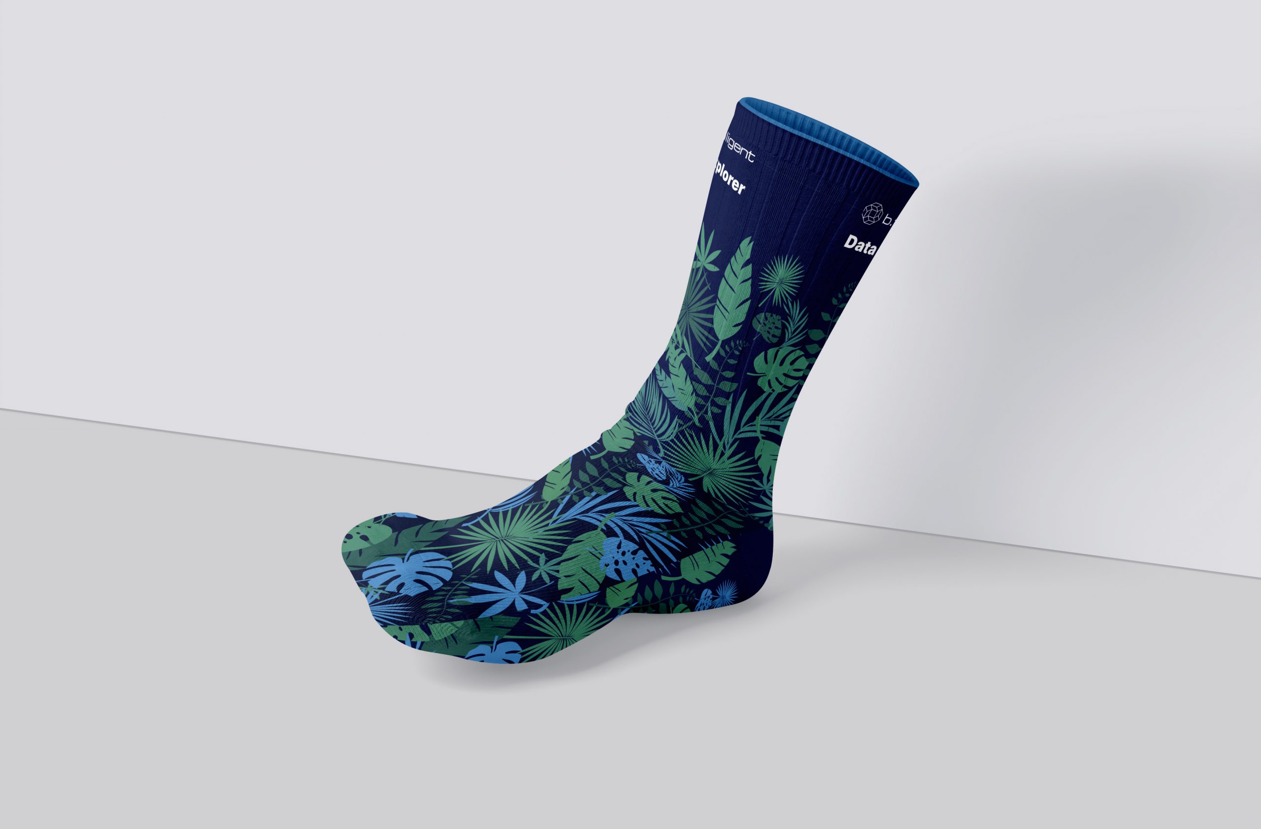 Data Explorer-Socken für b.telligent auf der FabCon Europe: Dunkelblaue Socken mit grün-blauen Dschungel-Pflanzenmotiven und den Aufdrucken ‚b.telligent‘ und ‚Data Explorer‘. Entworfen von Rebekka Markert, Grafikdesigner:in für kreative Merchandise-Ideen.