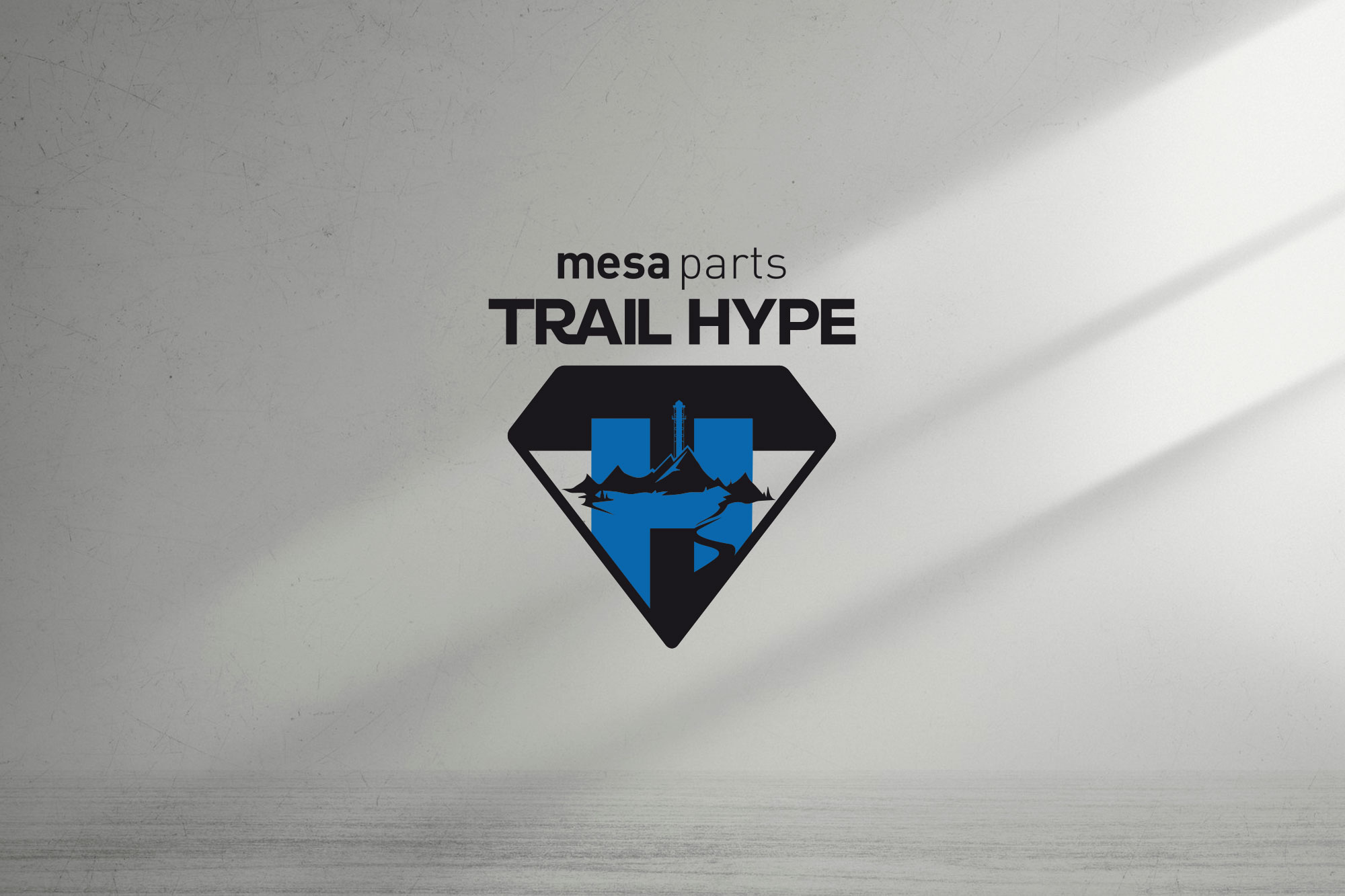 Mesa Parts Trail Hype Logo im Superman-Stil mit blauem H im schwarzen Diamantschild, Bergen und Fluss.